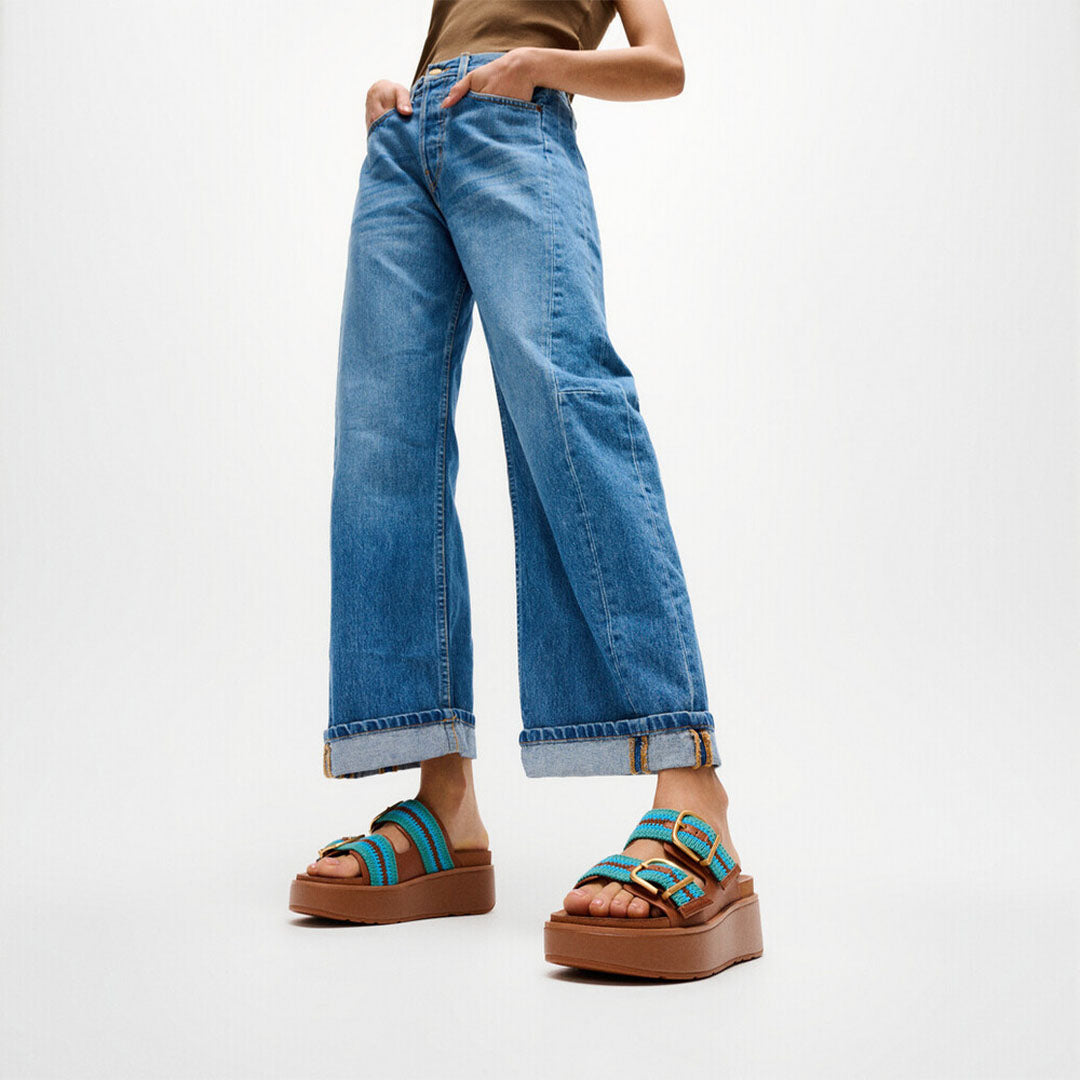 Woman wearing FitFlop GEN-FF Max Stripe-Webbing Two-Bar Slides with adjustable straps and a supportive chunky flatform sole.