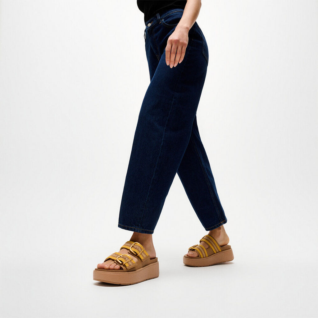 Woman wearing FitFlop GEN-FF Max Stripe-Webbing Two-Bar Slides with adjustable straps and a supportive chunky flatform sole.