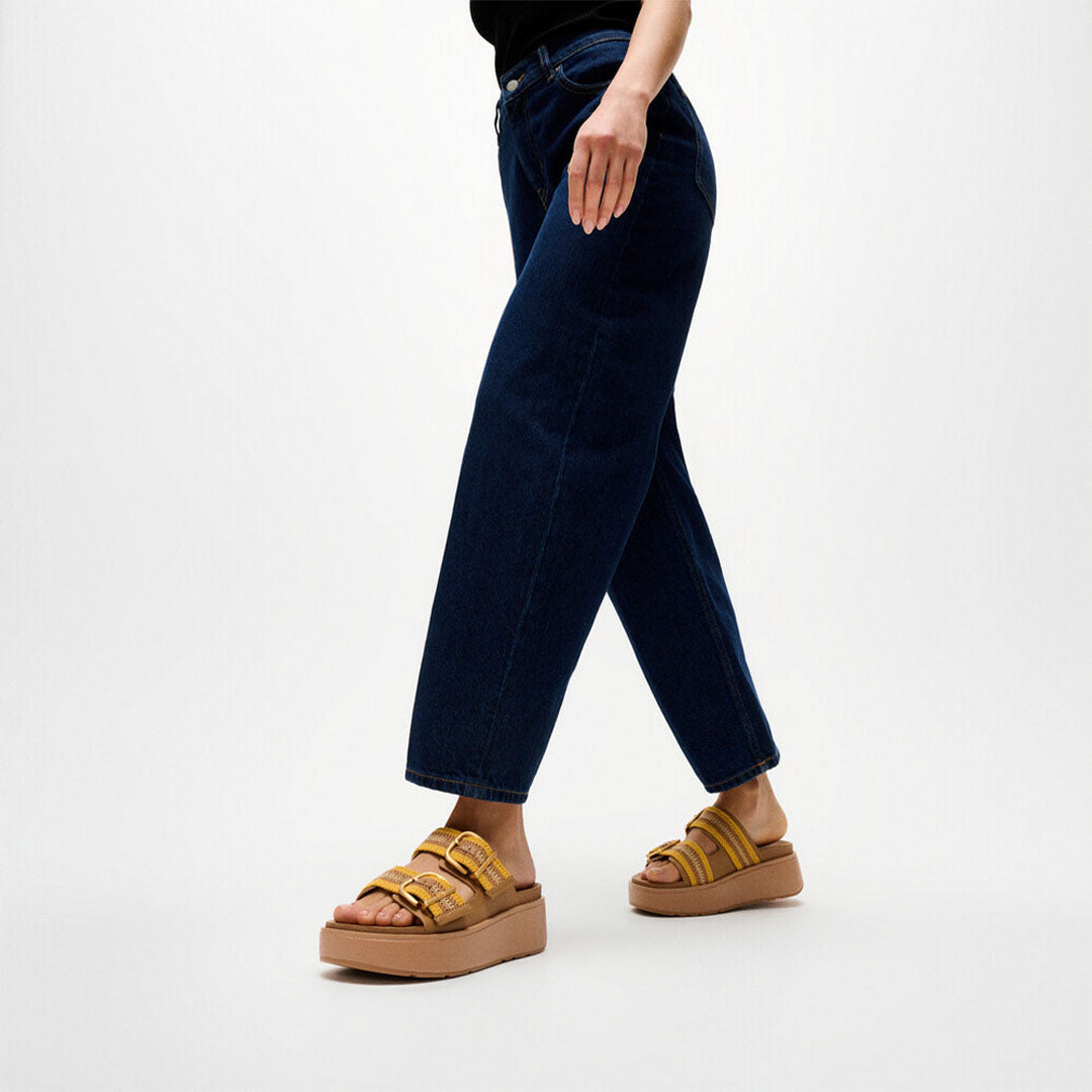 Woman wearing FitFlop GEN-FF Max Stripe-Webbing Two-Bar Slides with adjustable straps and a supportive chunky flatform sole.
