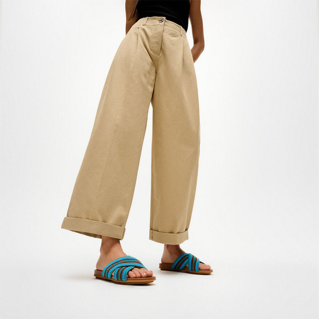 Woman wearing FitFlop GRACIE Stripe-Webbing Cross Slides with striped straps and lightweight cushioned sole.