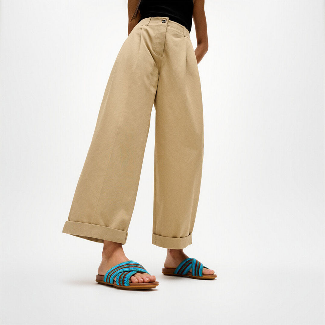 Woman wearing FitFlop GRACIE Stripe-Webbing Cross Slides with striped straps and lightweight cushioned sole.