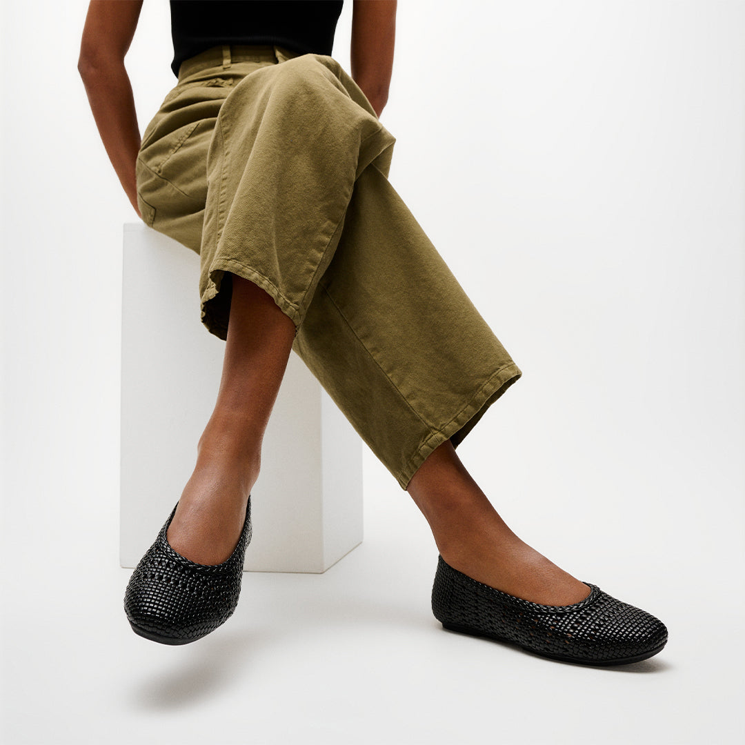 Woman wearing FitFlop DELICATO Woven PU Ballerinas with a woven faux-leather upper, lightweight comfort, and ergonomic support.