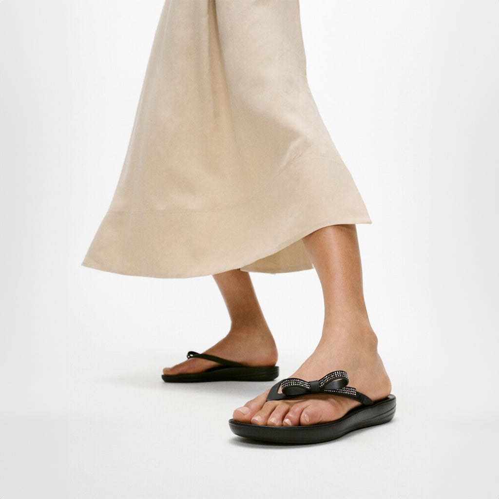 iQUSHION Glitz-Bow flip-flops with cushioned footbed, anatomically shaped straps, delicate bow detail, waterproof and lightweight.