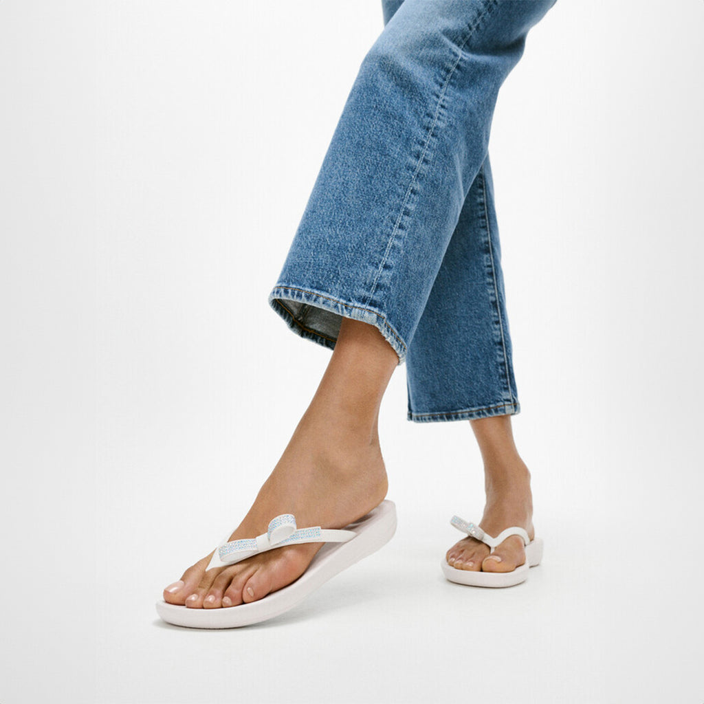 iQUSHION Glitz-Bow flip-flops with cushioned footbed, anatomically shaped straps, delicate bow detail, waterproof and lightweight.