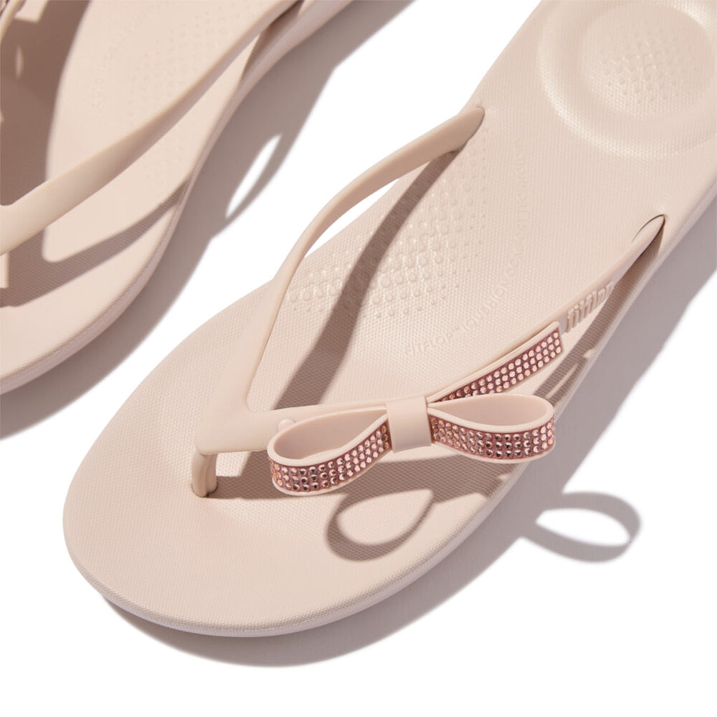 iQUSHION Glitz-Bow flip-flops with cushioned footbed, anatomically shaped straps, delicate bow detail, waterproof and lightweight.