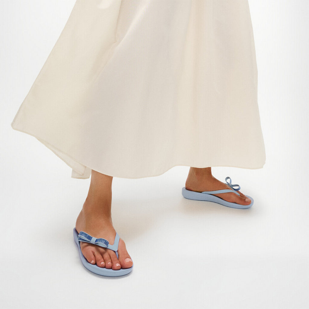 iQUSHION Glitz-Bow flip-flops with cushioned footbed, anatomically shaped straps, delicate bow detail, waterproof and lightweight.