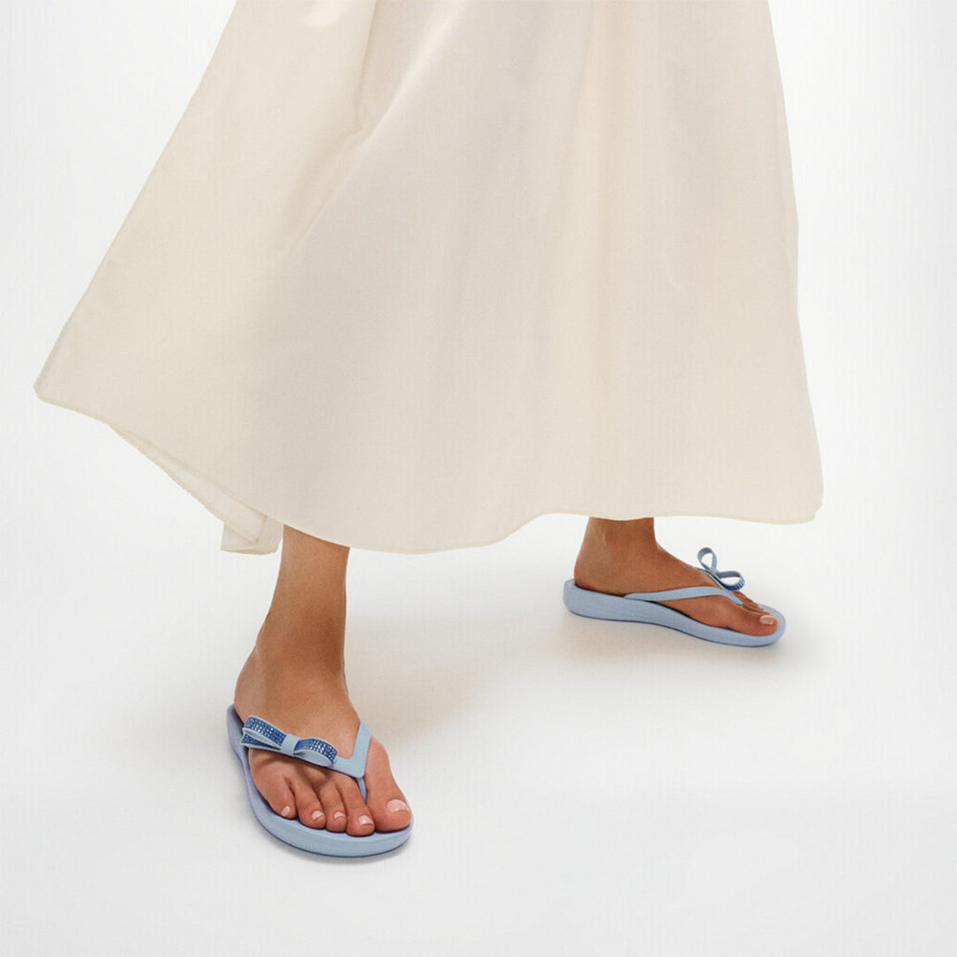 iQUSHION Glitz-Bow flip-flops with cushioned footbed, anatomically shaped straps, delicate bow detail, waterproof and lightweight.