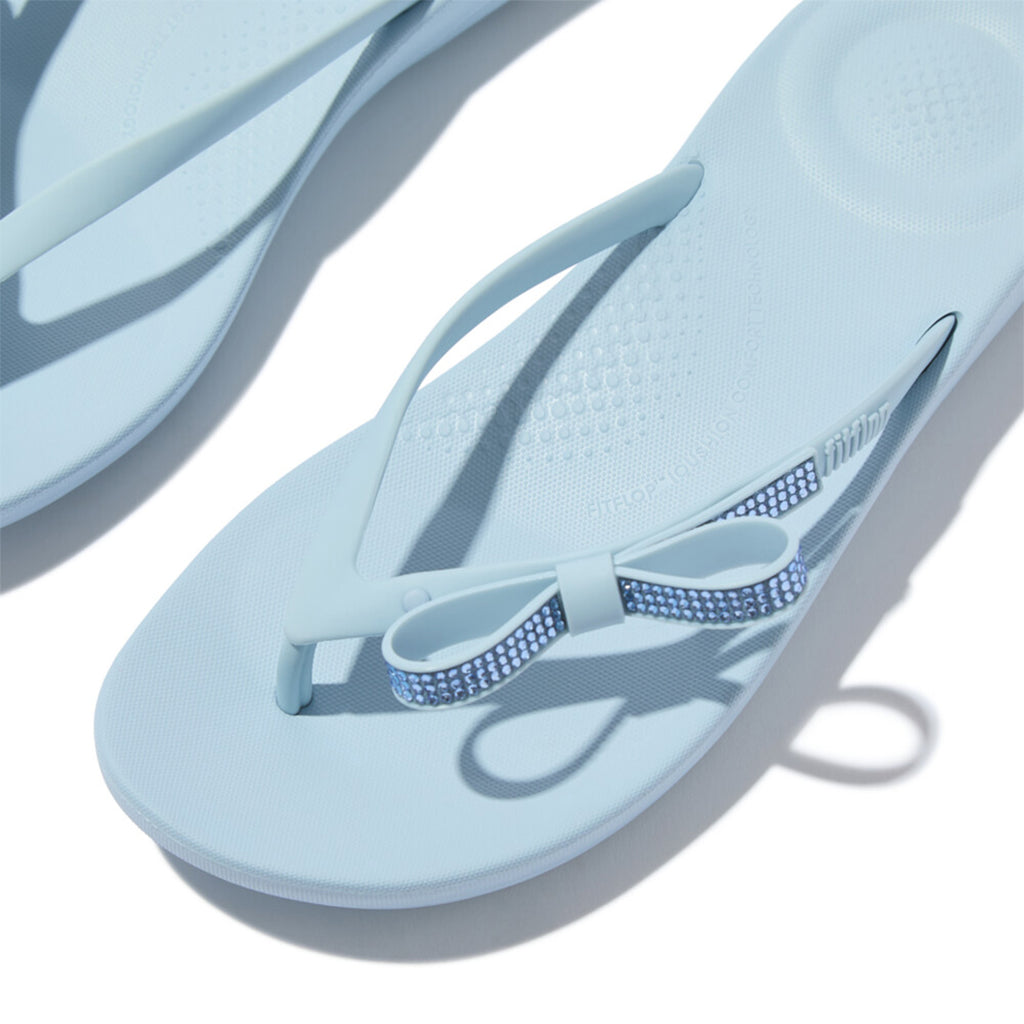 iQUSHION Glitz-Bow flip-flops with cushioned footbed, anatomically shaped straps, delicate bow detail, waterproof and lightweight.
