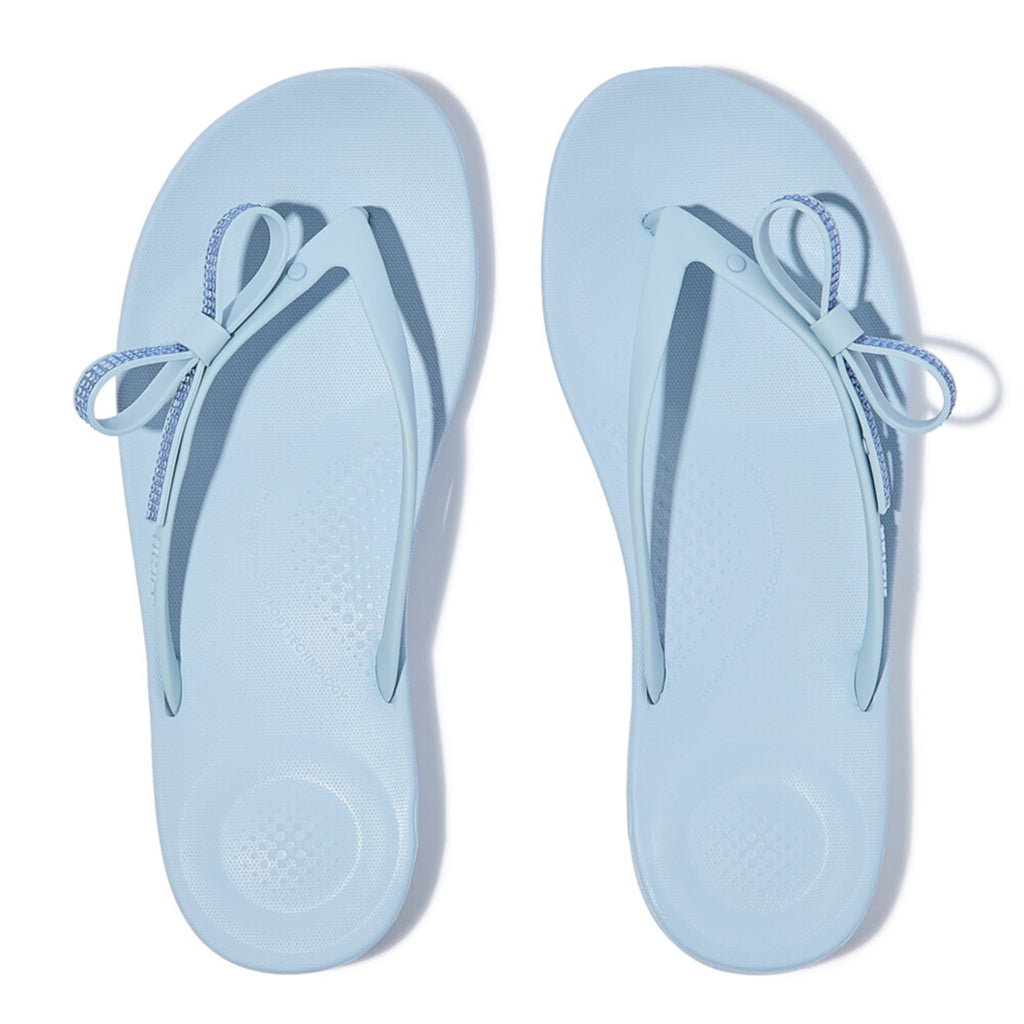 iQUSHION Glitz-Bow flip-flops with cushioned footbed, anatomically shaped straps, delicate bow detail, waterproof and lightweight.