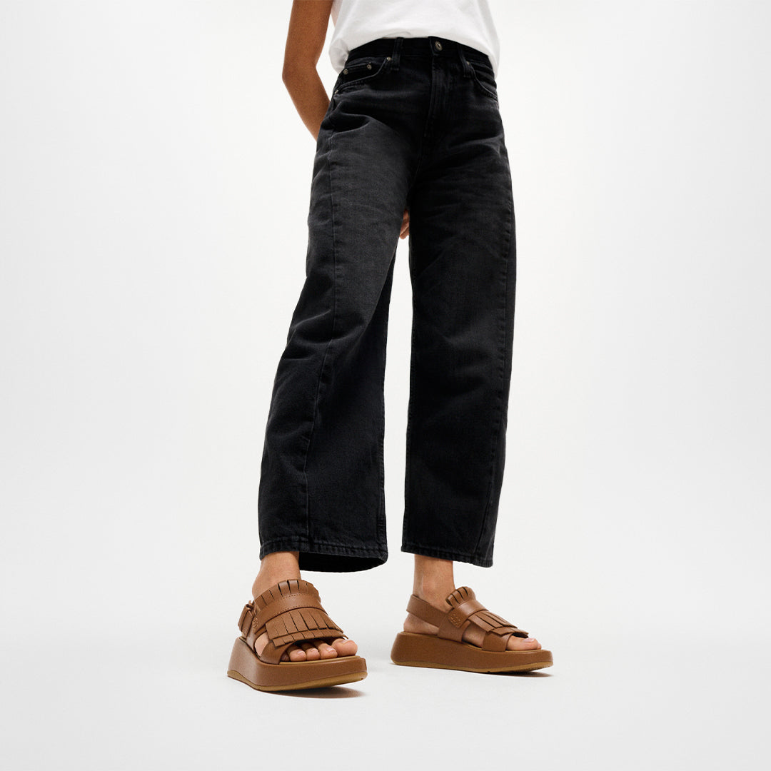 Woman wearing FitFlop F-MODE Fringe Sandals with premium leather, tassel-inspired fringe, and a supportive Microwobbleboard™ sole.