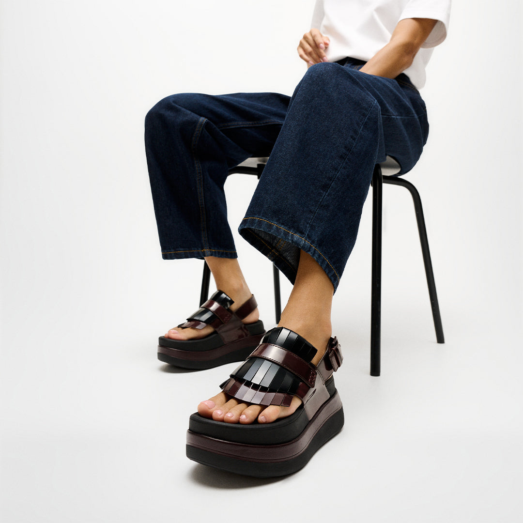 Woman wearing FitFlop F-MODE STACK Leather Fringe Sandals with premium leather construction, fringe trim, and cushioned platform sole.