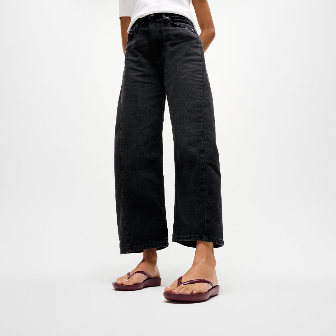 Woman wearing FitFlop iQUSHION Glitter Flip-Flops with glitter straps and ultra-lightweight ergonomic cushioning.