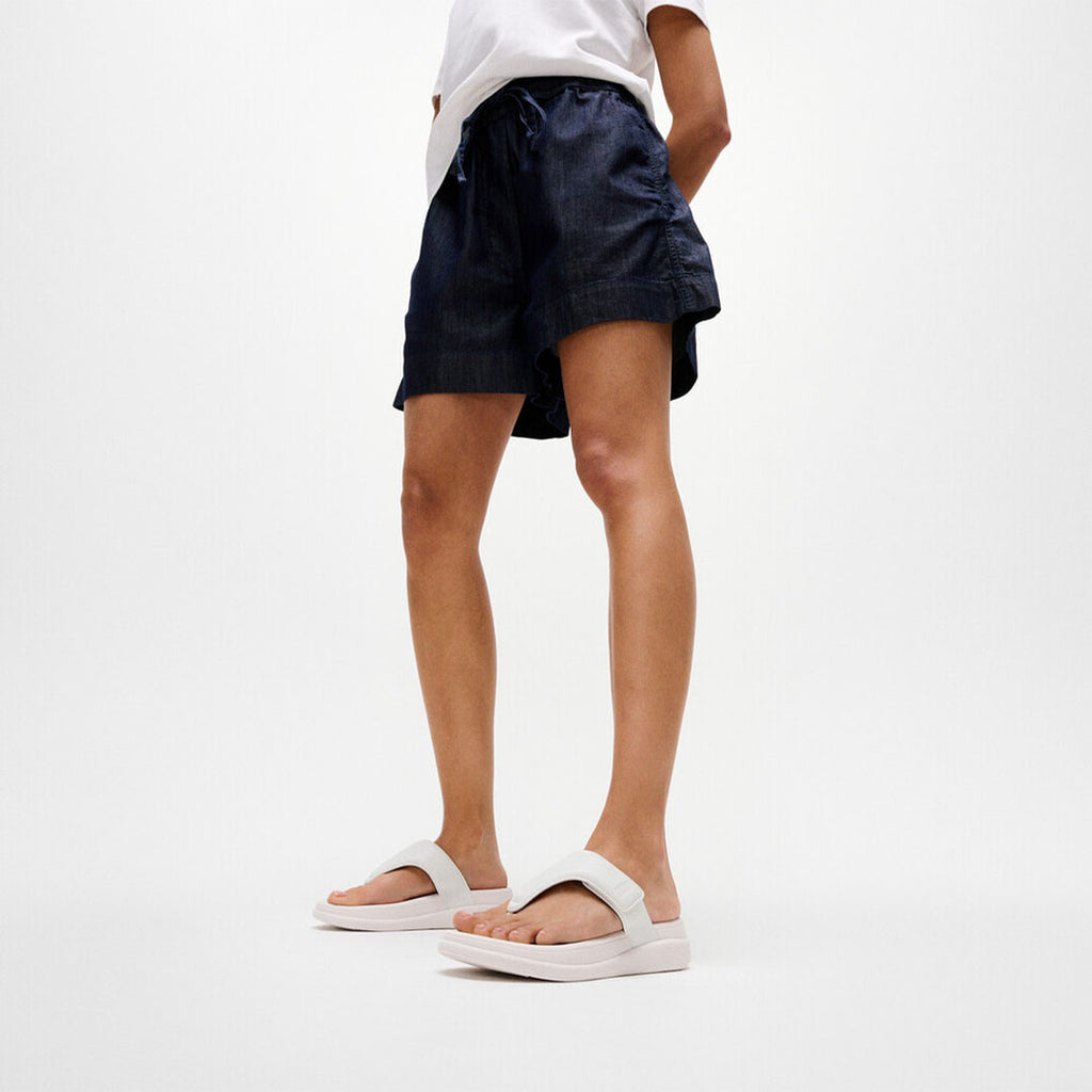 Woman wearing FitFlop F-MODE Go Toe-Post Sandals with metallic straps, ergonomic cushioning, and a lightweight flatform sole.