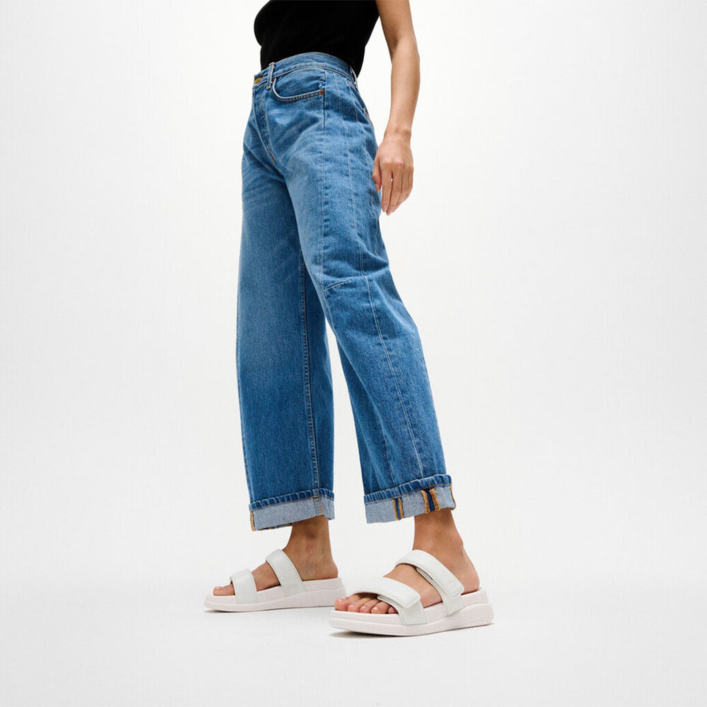 Woman wearing FitFlop F-MODE Go Two-Bar Slides with metallic straps, cushioned footbed, and lightweight flatform sole.