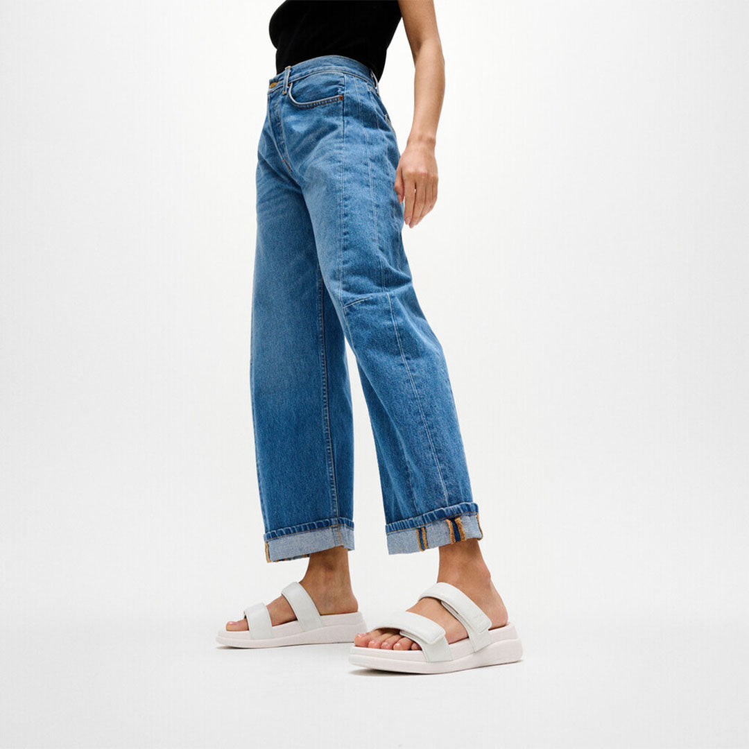 Woman wearing FitFlop F-MODE Go Two-Bar Slides with metallic straps, cushioned footbed, and lightweight flatform sole.