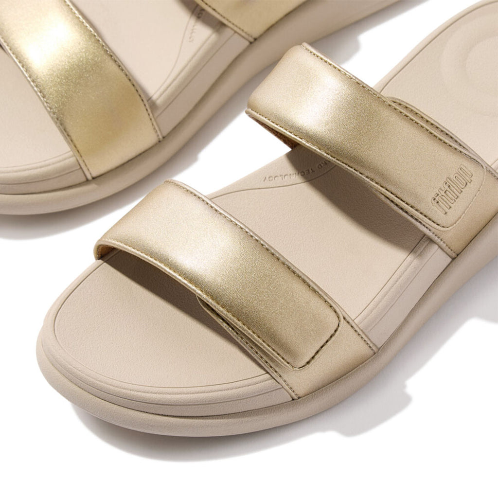 Close-up of FitFlop F-MODE Go Adjustable Slides featuring metallic faux-leather straps and soft padded detailing.