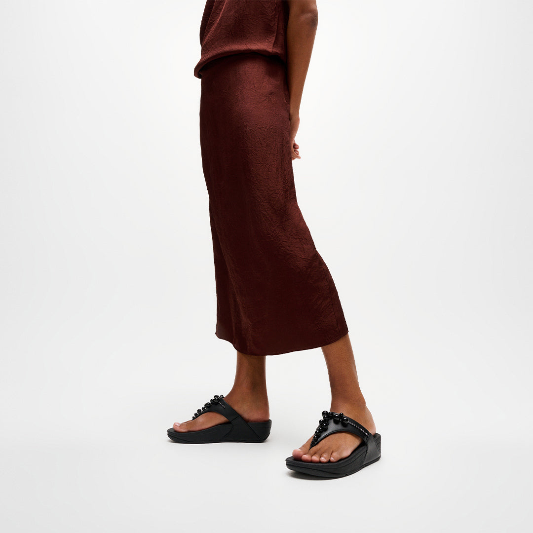 Woman wearing FitFlop LULU Beaded Toe-Post Sandals with embellished straps and supportive cushioned sole.