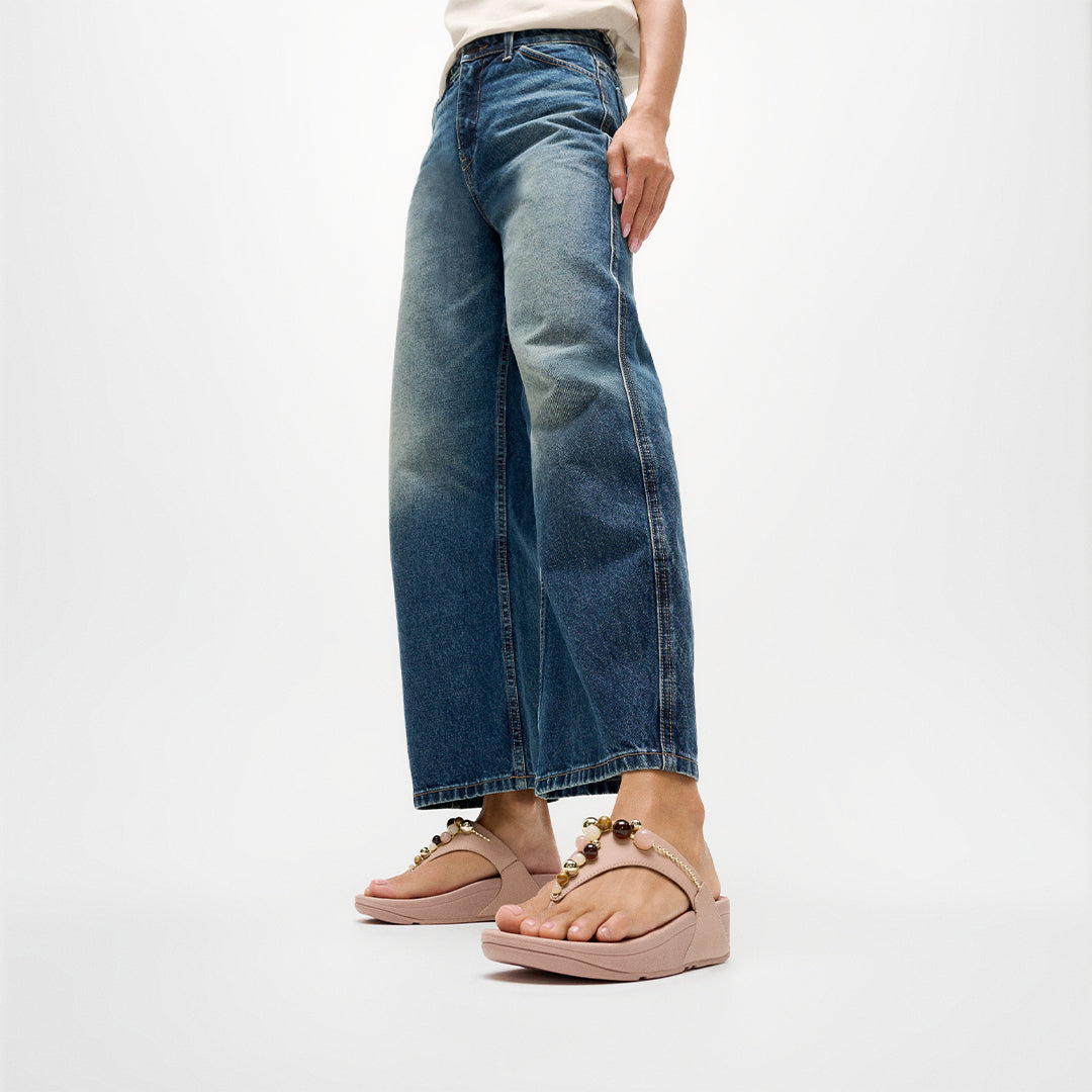 Woman wearing FitFlop LULU Beaded Toe-Post Sandals with embellished straps and supportive cushioned sole.