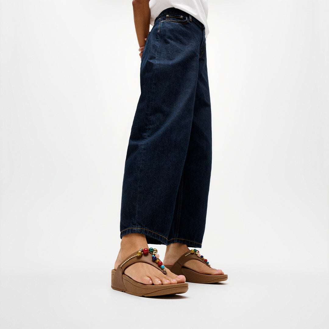 Woman wearing FitFlop LULU Beaded Toe-Post Sandals with embellished straps and supportive cushioned sole.