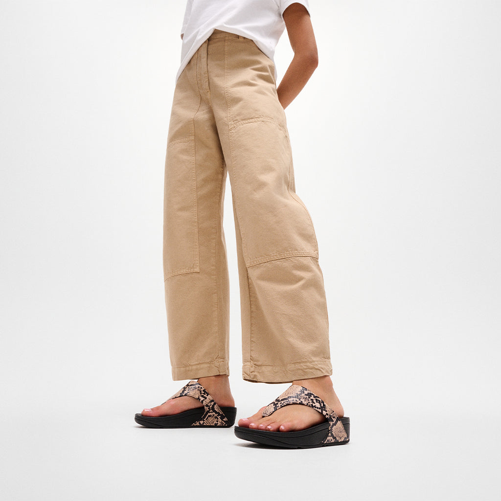 Woman wearing FitFlop LULU Snake Toe-Post Sandals with snake-effect leather straps and supportive cushioned sole.