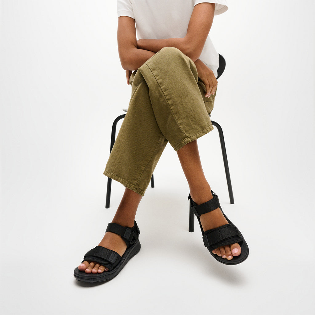 Person wearing FitFlop NEO-D-HYKER Outdoor Sandals featuring adjustable straps, ergonomic cushioning, and durable outdoor traction.