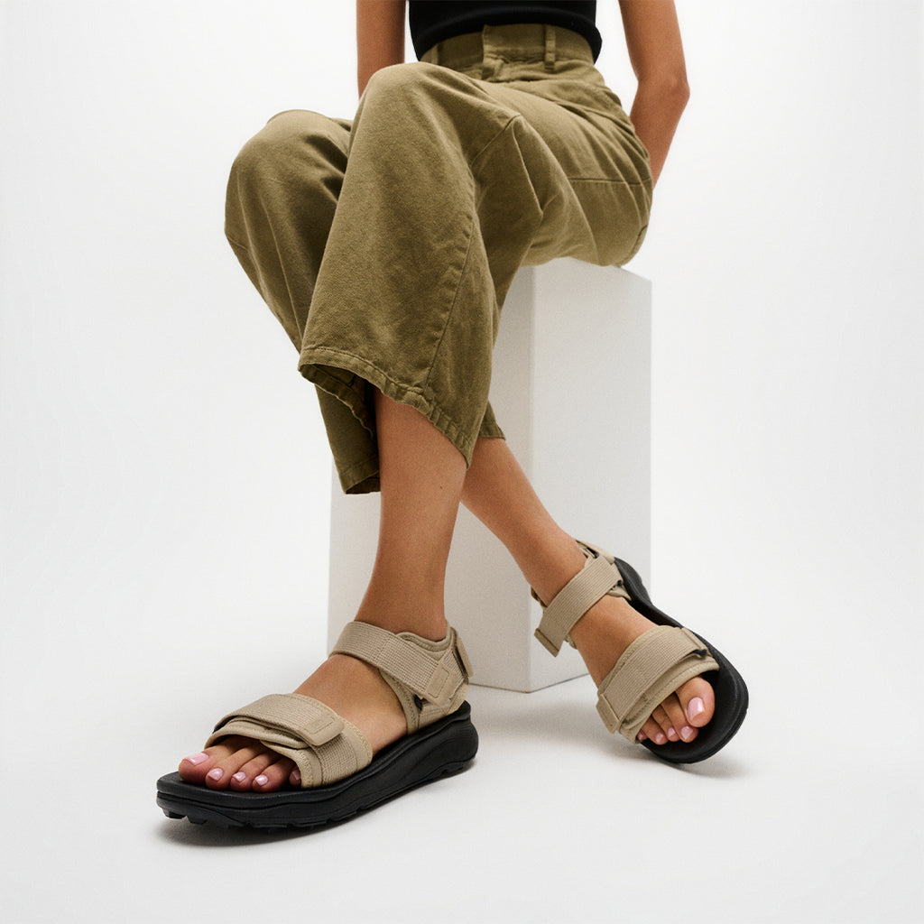 Person wearing FitFlop NEO-D-HYKER Outdoor Sandals featuring adjustable straps, ergonomic cushioning, and durable outdoor traction.