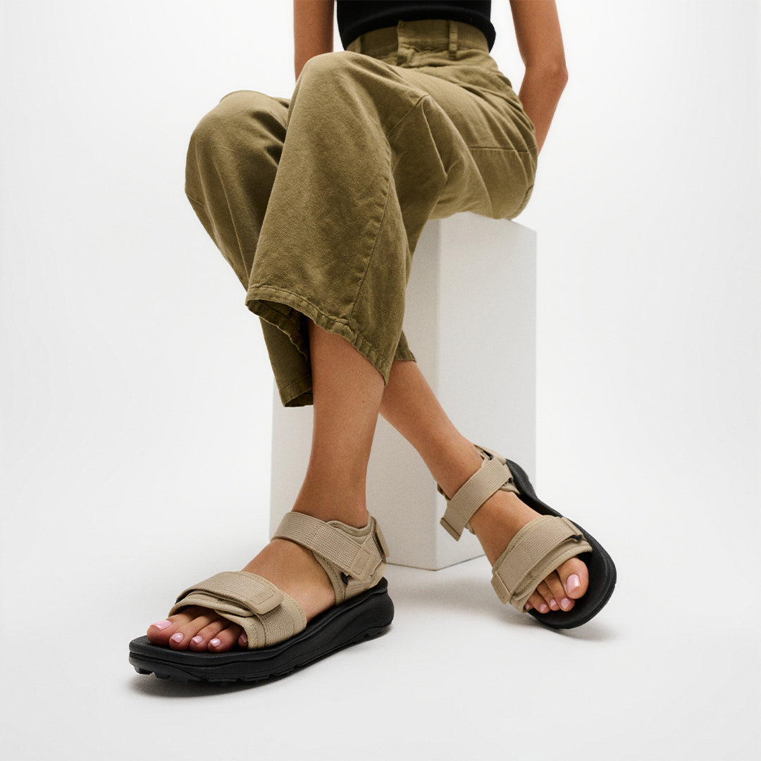 Person wearing FitFlop NEO-D-HYKER Outdoor Sandals featuring adjustable straps, ergonomic cushioning, and durable outdoor traction.